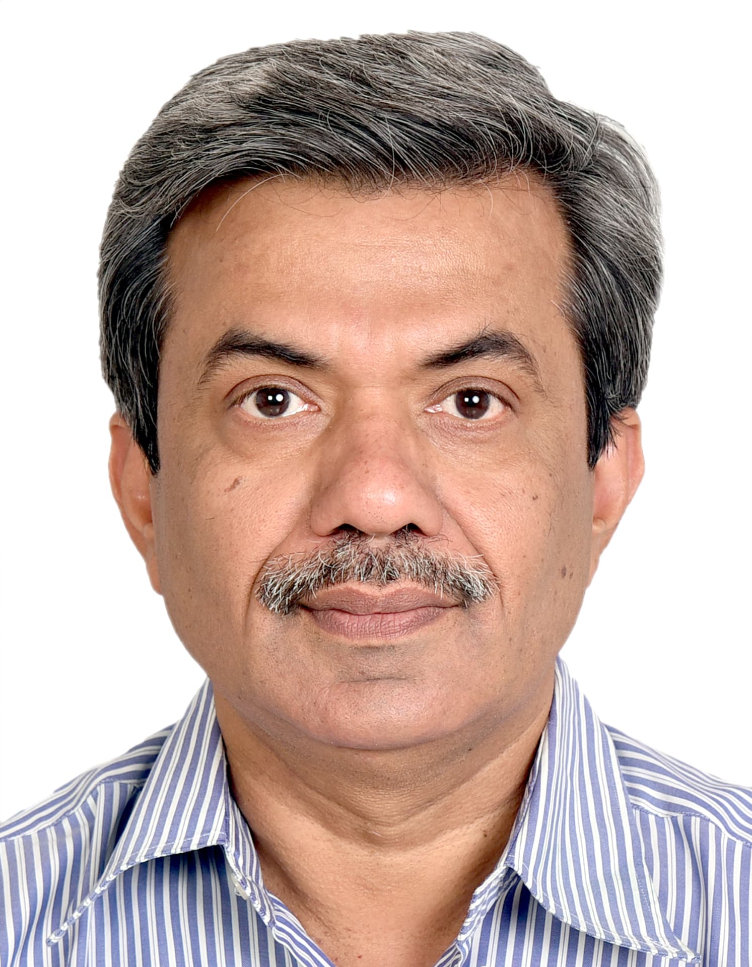 Retrato oficial de Yogesh Jain, homem de cabelos grisalhos e bigode, usando camisa listrada em azul e branco, sobre fundo claro.