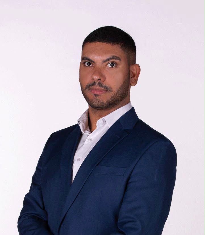 Retrato oficial de Thiago Teixeira, homem de cabelo curto, barba cerrada, sorrindo discretamente, usando camisa social clara e blazer azul-marinho, sobre fundo claro.