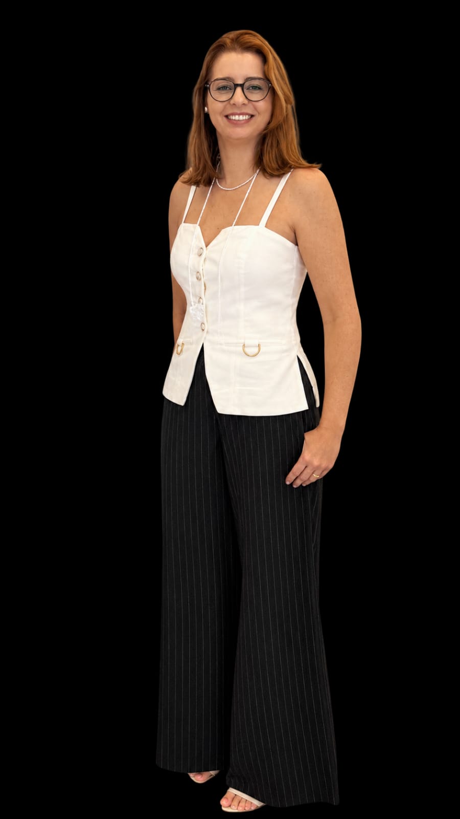 Retrato oficial da debatedora, mulher de cabelos castanho-avermelhados na altura dos ombros, óculos de armação escura, brincos pequenos e colar de pérolas, blusa branca de alcinhas com botões e calça social preta, sorrindo de corpo inteiro sobre fundo preto.