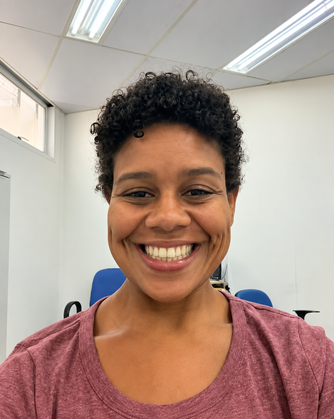 Retrato oficial de Rita Helena do Espírito Santo Borret, sorrindo, com cabelo curto cacheado e blusa rosa, em ambiente interno.