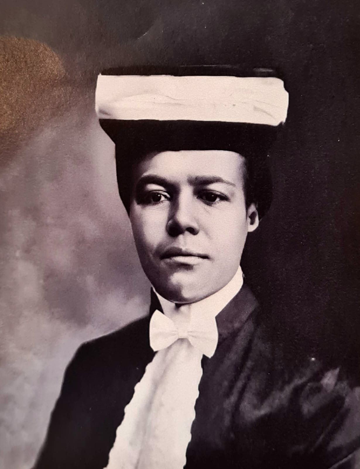 Retrato histórico em preto e branco de Maria Odília Teixeira com beca, capelo e gravata-borboleta clara.